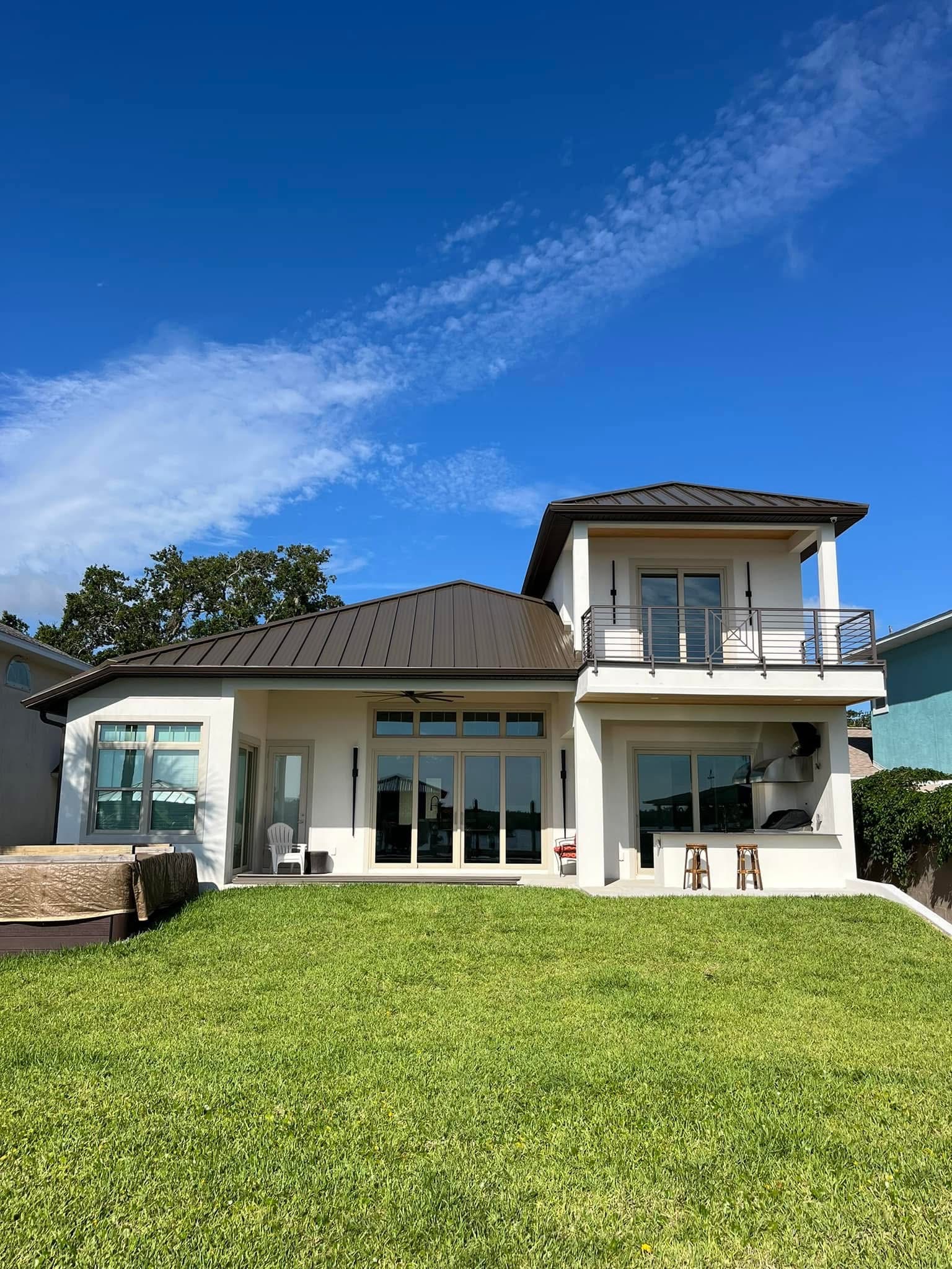 Niagara Builders waterfront custom home with metal roofs and a second-floor balcony